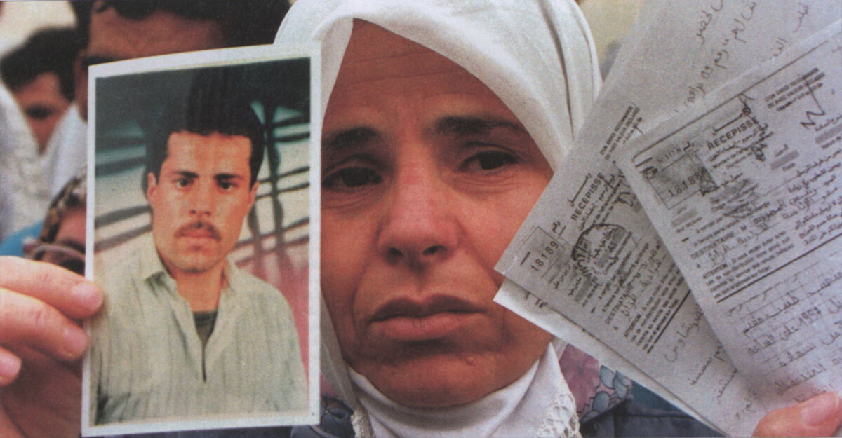 An Algerian woman holds up official papers and photo of a missing relative. (Popperfoto/Reuters)