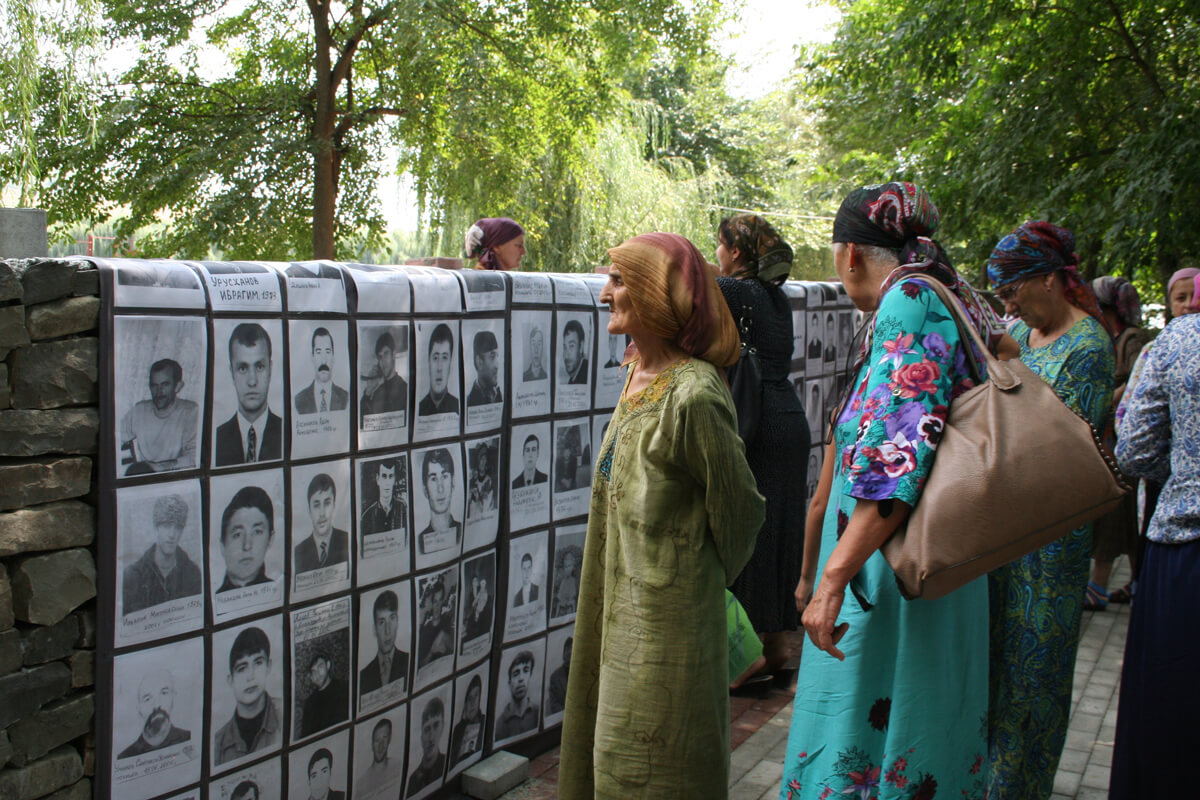Yakınları, kaybettikleri akrabalarının fotoğraflarına bakıyor. Çeçenistan, 2014. (ICRC/Zumrat Magomedova)